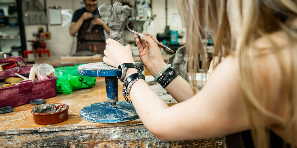 Art student creating a sculpture out of clay