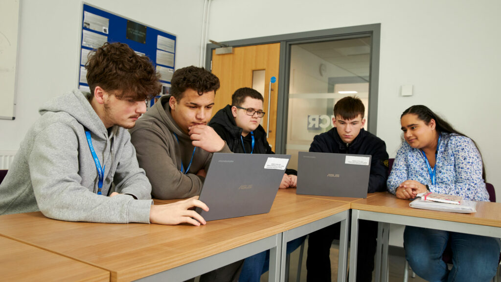 Business students sat at a table with laptops