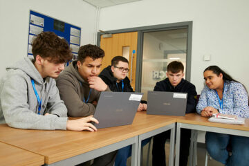 Business students sat at a table with laptops