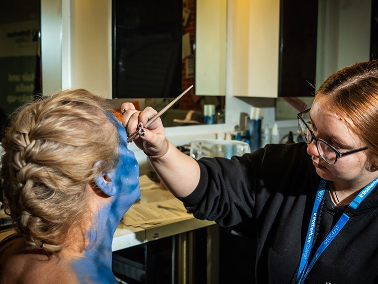 A media make-up student creating a theatrical look on a client