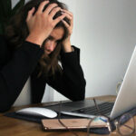 Lady sat in front of a laptop with her head in her hands