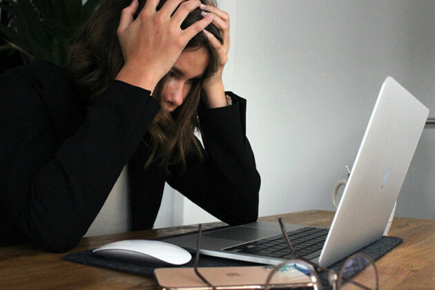 Lady sat in front of a laptop with her head in her hands