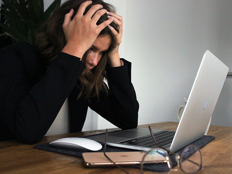 Lady sat in front of a laptop with her head in her hands