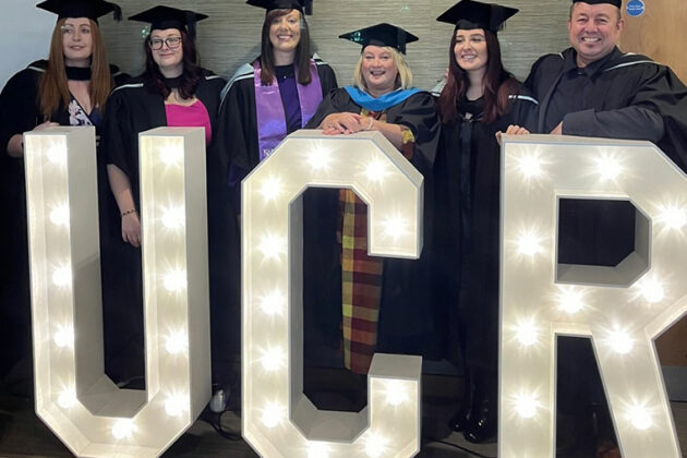 Students at their graduation stood at large UCR lit up letters
