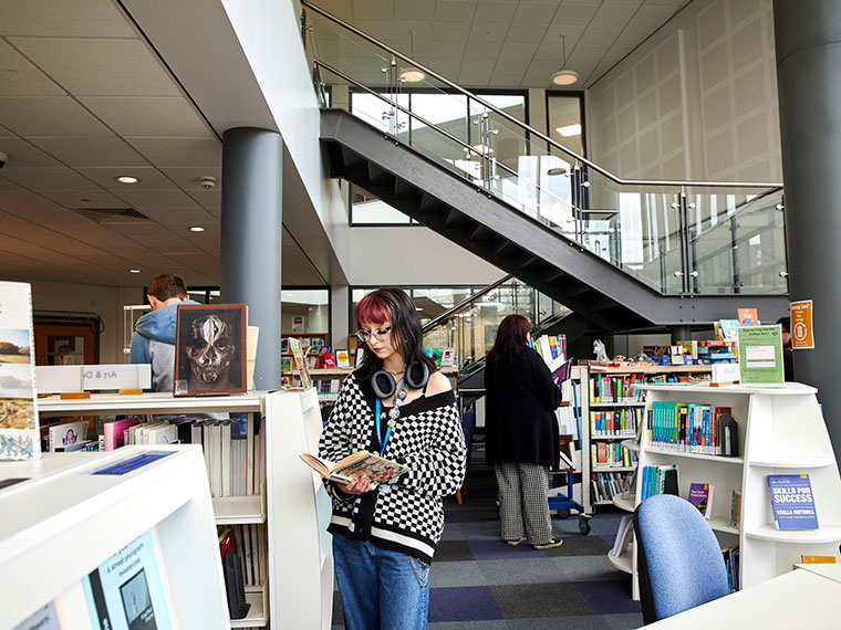 A student stood looking at a book in the UCR library