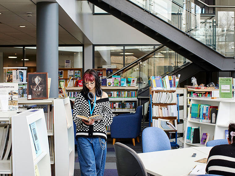 A student stood looking at a book in the UCR library