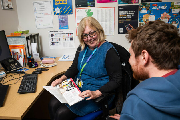 A member of staff sat at a desk speaking to someone