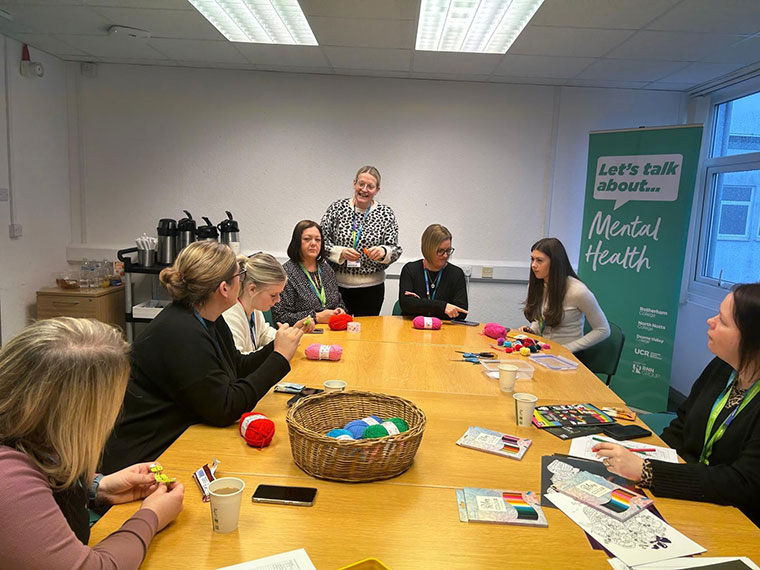 Staff sat around a large table taking part in crafts during a Time to Talk session