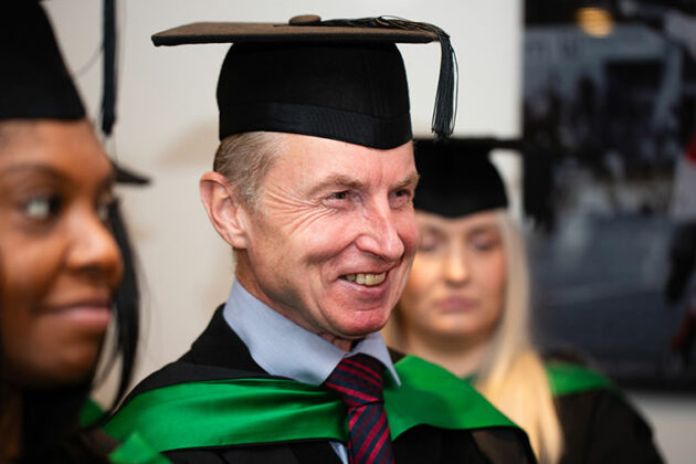 A head and shoulders shot of a smiliing student in graduation attire