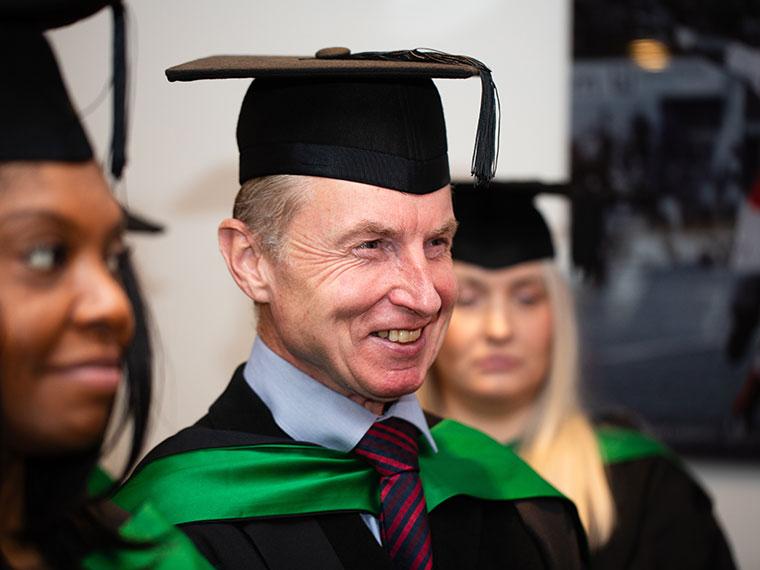 A head and shoulders shot of a smiliing student in graduation attire
