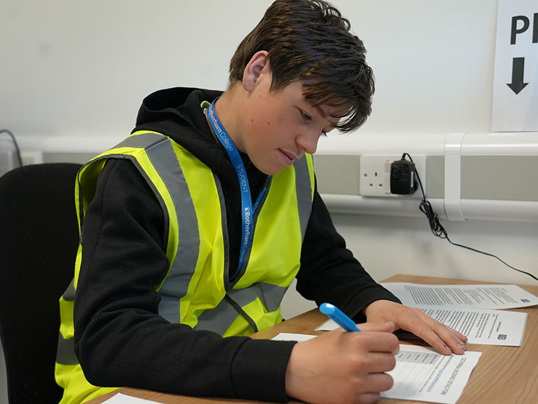 Someone wearing a high vis jacket sat at a desk writing