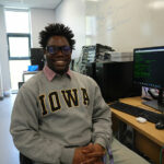 A student sat in a classroom smiling at the camera