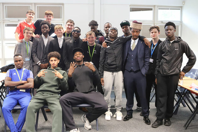 A large group of students sat and stood together in a classroom