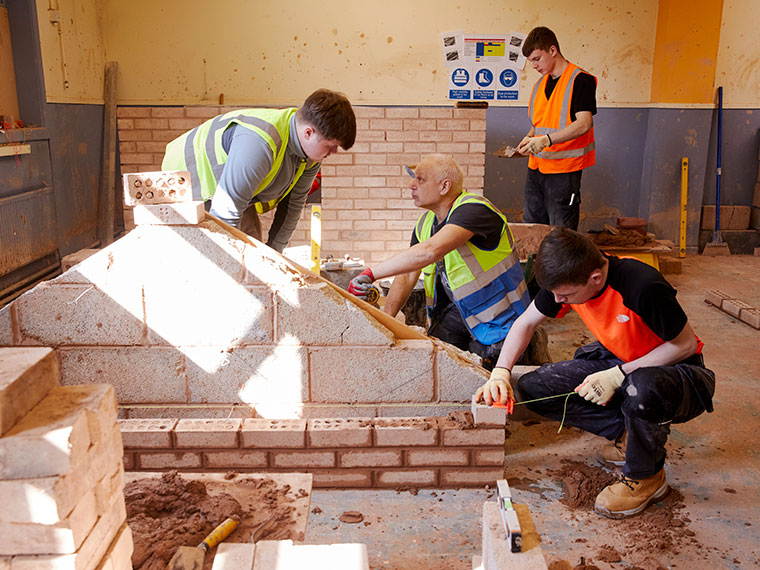 A tutor supporting students with their bricklaying project